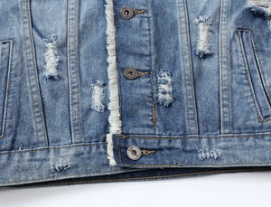 Macro detail of men's blue denim vest with ripped fabric and vintage metal buttons