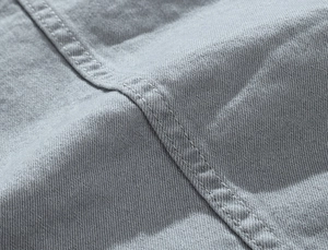 Close-up of grey washed denim fabric texture with professional double stitching detail