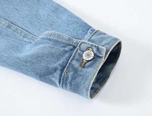 Detail van de manchet van het denim jack met gele stiksels en een metalen knoop