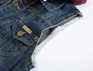Vue détaillée du tissu denim bleu foncé avec des coutures jaunes et un logo métallique