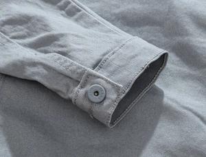 Detailed macro view of gray denim jacket cuff featuring twill fabric and jeans buttons