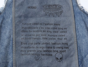Detail of blue denim vest featuring gray patch print with street style graphics and raw edges