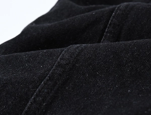 Gros plan détaillé sur la texture du denim noir épais et les coutures renforcées