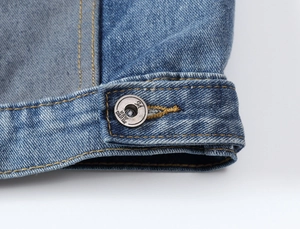 Macro shot of blue denim hem with vintage metal button and yellow contrast stitching