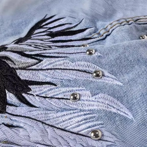 Men's light blue denim vest featuring detailed wing embroidery and silver metal studs