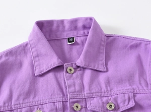 Detail of purple denim jacket collar with black size tag and branded metal buttons