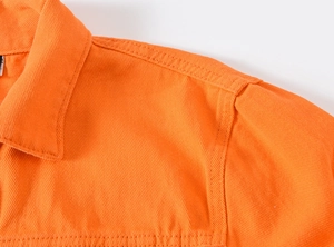 Detail der hellorangen Jeansjacke mit Twill-Stoffstruktur und hochwertigen Nähten