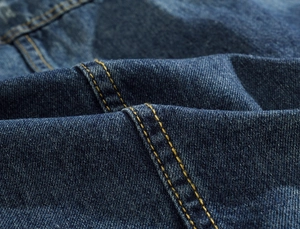 Détail du tissu denim bleu foncé avec doubles coutures dorées renforcées de qualité