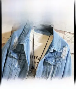 Detailed view of light blue distressed denim jacket with frayed edges and metal pendants