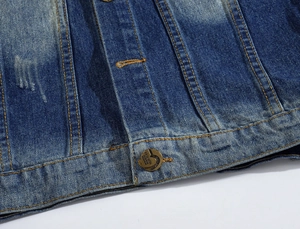 Close-up of washed blue denim fabric with orange stitching and vintage FASHION button