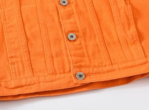 Makroaufnahme der orangefarbenen Jeansjacke mit Silberknöpfen und Köperstruktur