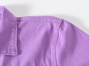 Detailed view of light purple denim jacket shoulder and collar with neat stitching