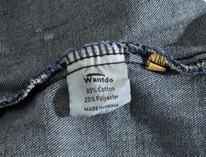 Close-up of the care label on men's denim vest showing 80% cotton and 20% polyester blend