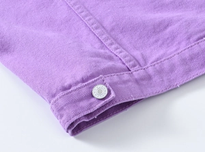 Gros plan sur le denim violet avec un bouton argenté gravé de l'inscription JEANS