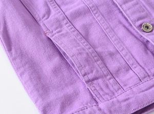 Close-up of light purple denim jacket texture with silver metal buttons and stitching