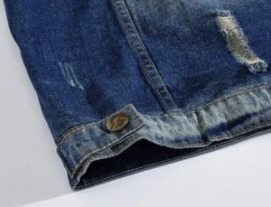 Detail of denim vest with vintage brass button, orange stitching, and distressed wash finish