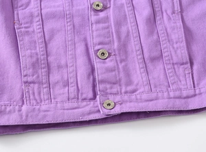 Detailed macro view of purple denim jacket fabric texture and engraved metal buttons