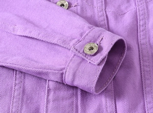Detail of purple denim jacket cuff with embossed silver metal button and precise stitching