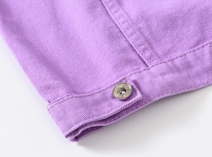 Detailed close-up of purple denim jacket fabric with a textured metal button and stitching