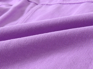 Detailed macro view of lavender purple twill fabric with precision stitching on a jacket