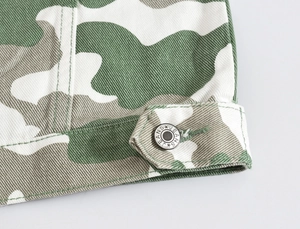 Macro detail of military camo jacket showing metallic button with engraved jeans text