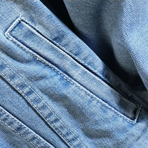 Men's light blue denim jacket featuring premium twill texture and white reinforced stitching