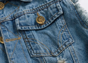 Macro view of blue denim vest detail with bronze button and yellow stitching accents