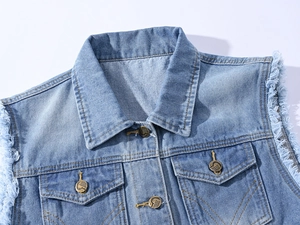 Gros plan sur le gilet en jean bleu clair avec boutons en métal et emmanchures effilochées