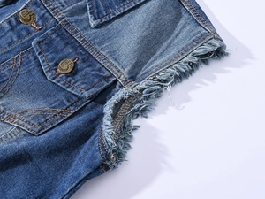 Detailed macro view of frayed cuffs and metal buttons on a dark blue washed denim vest