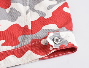 Detail of red camouflage denim jacket hem showing star-engraved metal button
