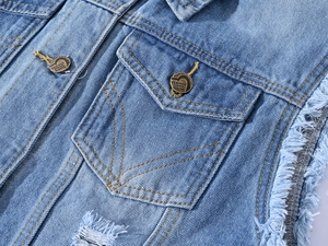Détail d'un gilet en jean bleu clair avec boutons en métal vintage et bords effilochés