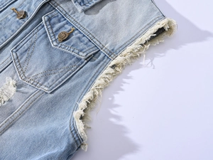Close-up of light blue denim vest showing distressed raw edges and vintage metal buttons