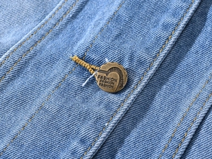 Détail macro du bouton en métal bronze rétro avec gravure sur gilet en jean bleu clair