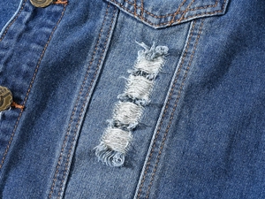 Detail of ripped denim vest with orange contrast stitching and bronze metal button