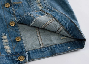 Detail of blue denim vest featuring distressed rips and vintage bronze buttons with engraving