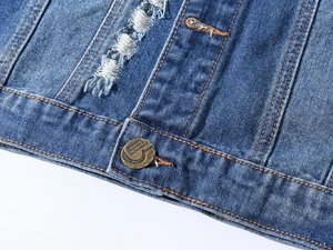 Macro shot of blue denim vest featuring orange stitching and distressed hole details