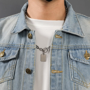 Close-up of silver OT buckle chain necklace with rectangular GRA pendant on denim jacket