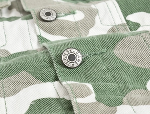 Detailed macro shot of vintage metal jeans buttons on a camouflage denim jacket fabric