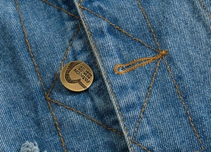 Macro shot of blue denim vest featuring diamond quilting and vintage metal button details