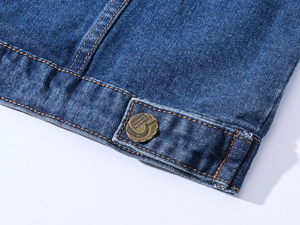 Detailed close-up of distressed denim hem featuring a vintage bronze button with fashion text