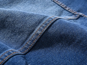 Close-up of dark blue denim fabric with precise yellow double stitching details
