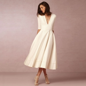 Detailed view of elegant ivory satin dress with deep V-neck and pleated A-line skirt