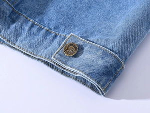 Vue macro du gilet en jean bleu clair montrant les boutons en bronze et les coutures jaunes