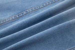 Gros plan sur la texture du denim bleu clair avec détails de double couture orange