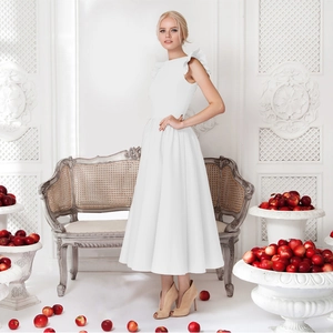 Elegant white mid-length dress with ruffle sleeves and high waist on a creative studio background