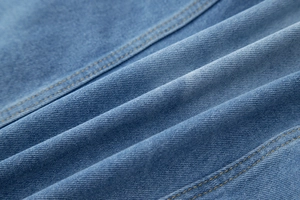Gros plan sur la texture du denim bleu clair avec des surpiqûres contrastées jaunes précises