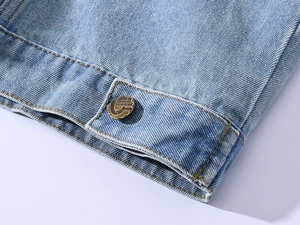 Detailed close-up of light blue denim hem with yellow stitching and metal fashion button