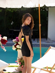 Chic black bodycon dress with puff sleeves and back cutout detail by the pool