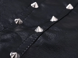 Macro shot of silver metal rivets on black pebbled leather vest with detailed stitching