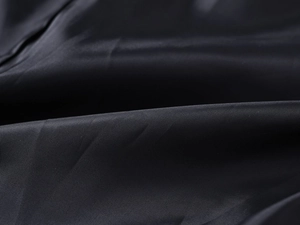 Close-up of black synthetic fiber fabric with fine woven texture and silk-like finish